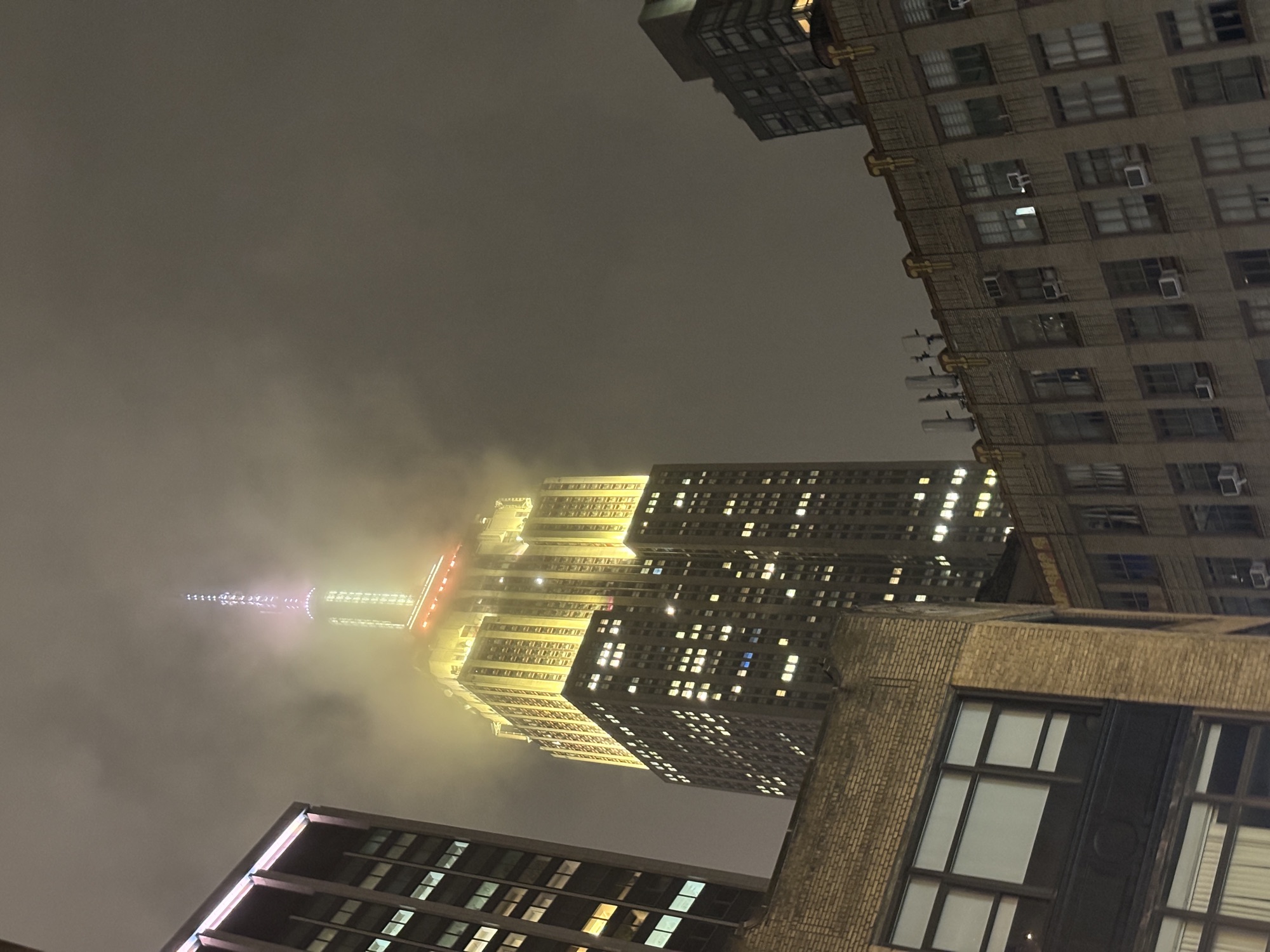 The Empire State Building lit gold in the fog